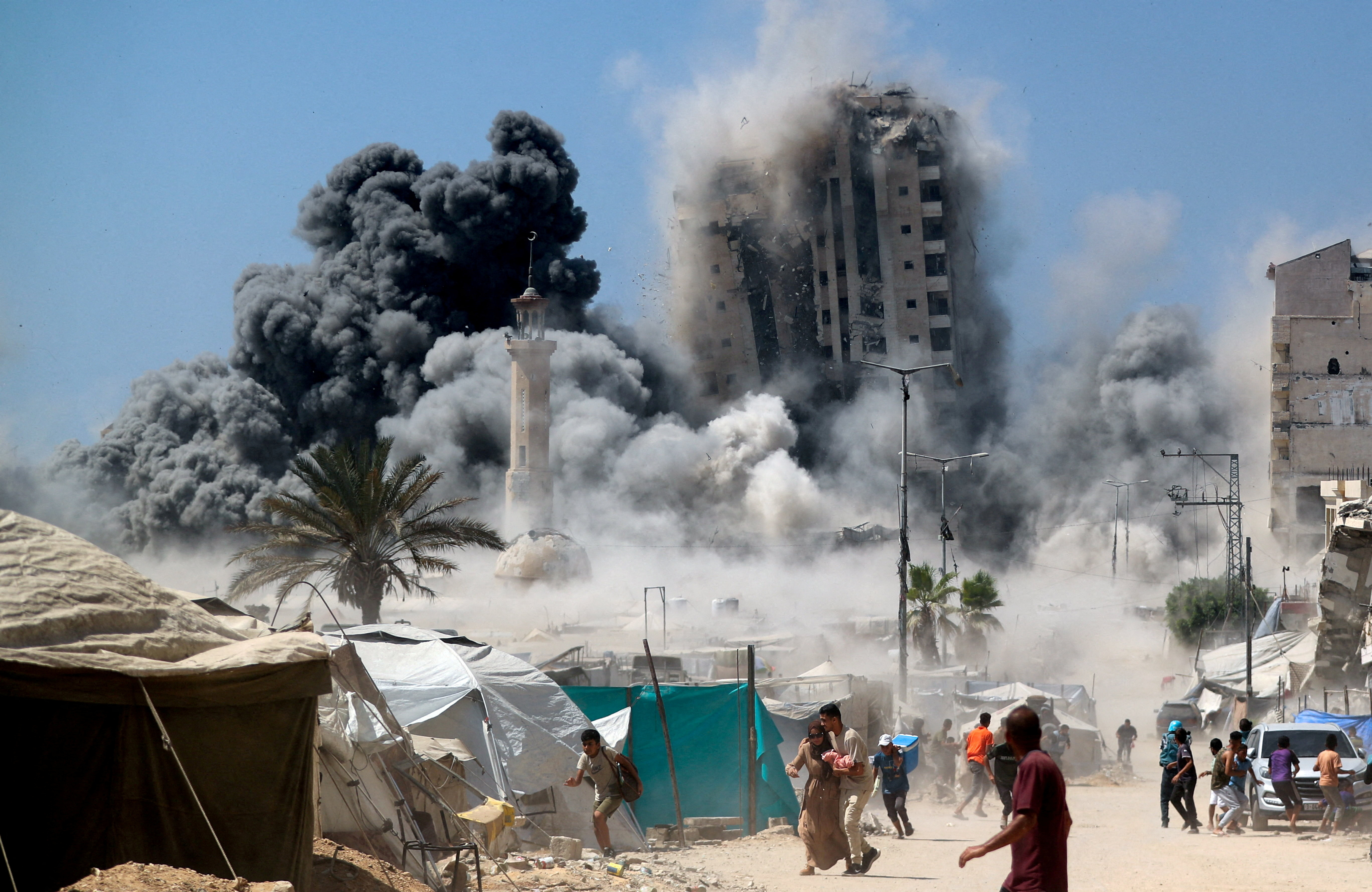 Palestinians run as the 15-storey Mushtaha Tower collapses after being hit by an Israeli air strike, in Gaza City. (REUTERS)